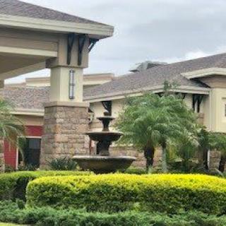 A beautifully landscaped area with a fountain in front of modern buildings.