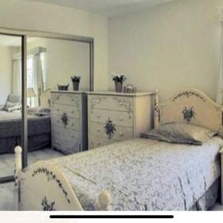A cozy bedroom with a single bed, floral bedding, and mirrored closet doors.