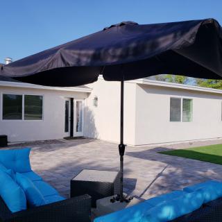 A sunny backyard featuring patio furniture with a large umbrella.