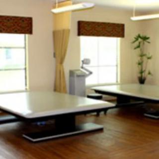 A spacious room with large tables and natural light from the windows.