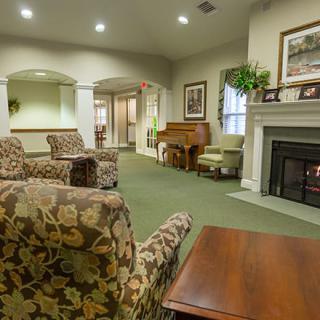 A cozy living room featuring comfortable seating, a fireplace, and a piano.