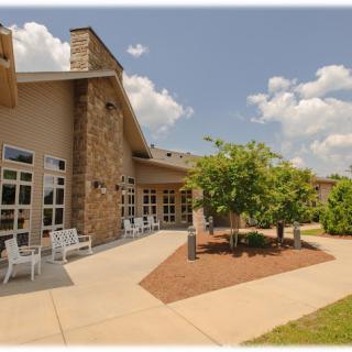 A modern building with a stone facade and well-maintained outdoor area under a clear, sunny sky.