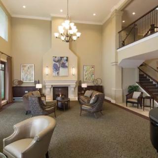 A spacious living room with elegant furniture and a chandelier, featuring a fireplace and modern decor.