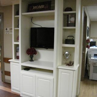 A modern white entertainment center featuring shelves for decor and a TV.
