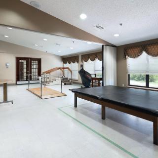 A rehabilitation center therapy room equipped with parallel bars and other exercise equipment.