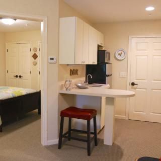 A cozy kitchenette area adjacent to a bedroom in a small apartment.