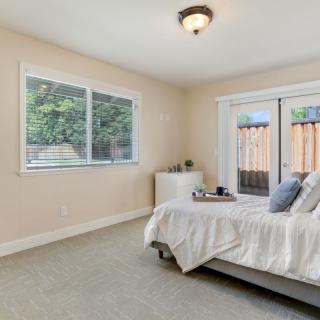 A bright and minimalist bedroom with a bed, window, and sliding glass door leading outside.