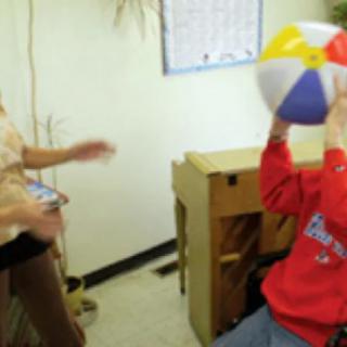 A child holding a colorful beach ball in a classroom setting.