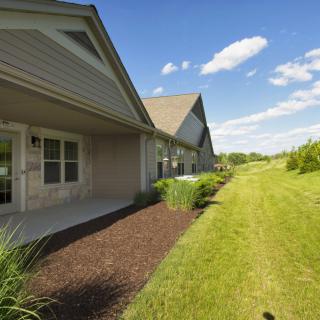 A view of modern residential homes with a well-maintained lawn and garden under a clear blue sky.