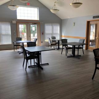 An empty indoor dining area with tables and chairs arranged on a wooden floor.