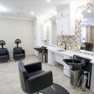 A modern hair salon interior with styling chairs, mirrors, and hair washing stations.