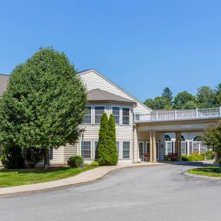A two-story building with a covered driveway and surrounded by trees on a clear day.