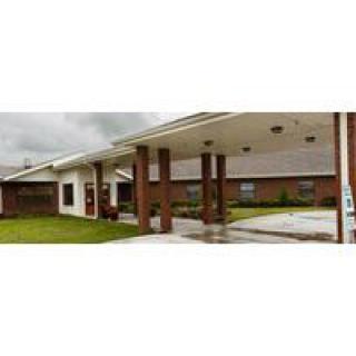 A brick building with an entrance and overhanging roof on a cloudy day.