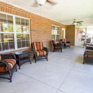 A spacious patio area with comfortable chairs and a brick wall backdrop.