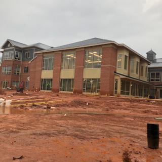 A view of a new building under construction, surrounded by red dirt.