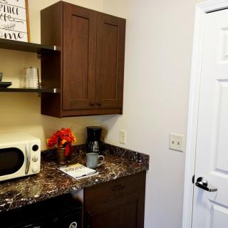 A small kitchen corner with a microwave, coffee maker, and decorative items on a marble countertop.