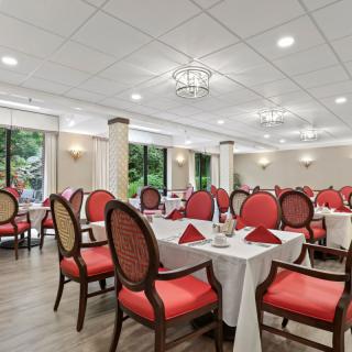 An elegant restaurant dining room with red upholstered chairs and neatly set tables.