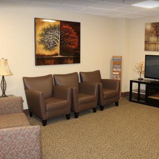 A cozy waiting room with chairs, a sofa, and a television.