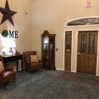 A cozy living room with chairs, a grandfather clock, and a decorated entrance.