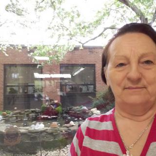 A woman takes a selfie indoors with a view of a garden through the window.