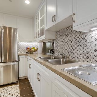 A modern kitchen with white cabinets, stainless steel appliances, and a decorative tile backsplash.