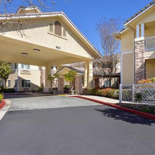 A residential building entrance with a covered driveway under a clear blue sky.