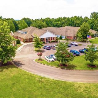 Aerial view of a building with a surrounding parking lot and lush greenery.