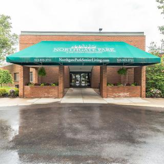 Entrance of a building with a green awning and brick exterior.