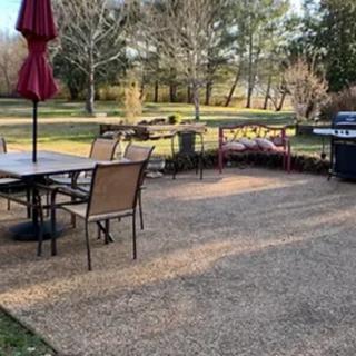 A cozy backyard patio with a dining set, umbrella, and grill overlooking a scenic landscape.