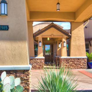 Entrance of a building featuring stucco walls and desert landscaping.