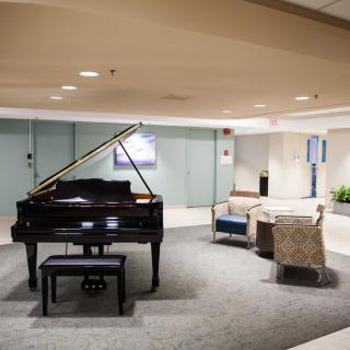 A grand piano in a modern lobby with comfortable seating.