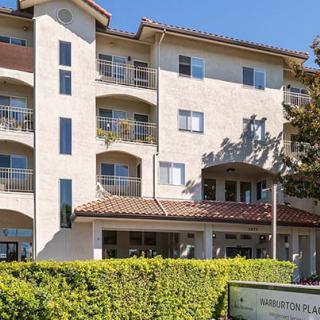 A multi-story residential apartment building with balconies and a landscaped front.