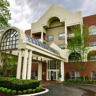 A modern hotel entrance with landscaped gardens and classic architectural features.