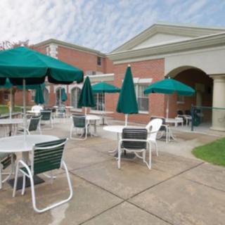 Outdoor patio with tables, chairs, and umbrellas in front of a brick building.