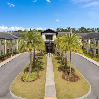 Aerial view of a modern apartment complex surrounded by palm trees and clear blue skies.