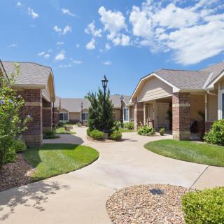 A peaceful residential neighborhood with neatly maintained houses and gardens under a blue sky.