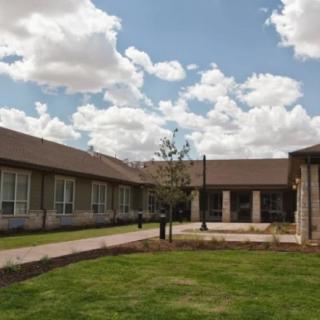A modern building with a courtyard, set under a partly cloudy sky.