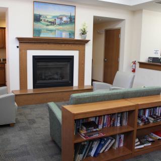 A cozy living room with a fireplace and bookshelf.