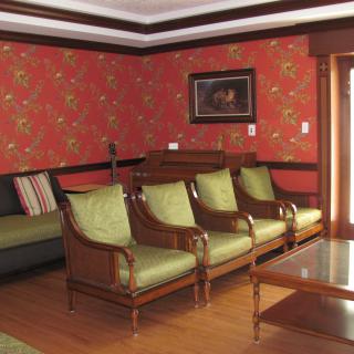 A classic living room with green upholstered chairs, a dark sofa, and wooden accents.