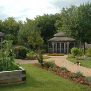 A serene garden featuring a gazebo, lush greenery, and a winding pathway.