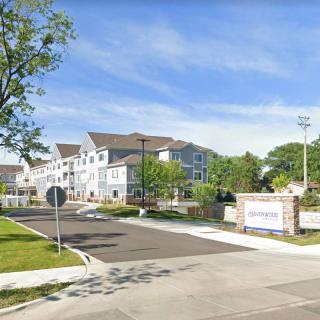 Entrance to a modern apartment complex with surrounding greenery.
