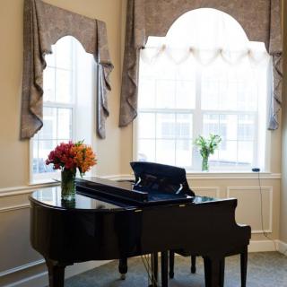 A grand piano adorned with a bouquet of flowers in a well-lit room with elegant curtains.