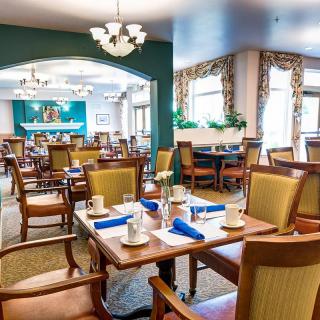 A well-arranged dining area with elegantly set tables, featuring comfortable chairs and chic chandeliers.