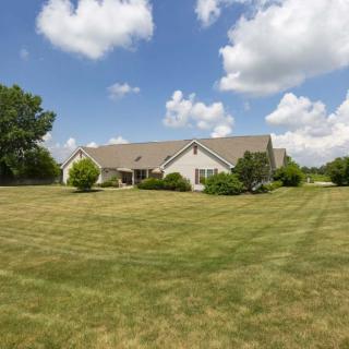 A suburban house with a large, well-maintained lawn under a partly cloudy sky.