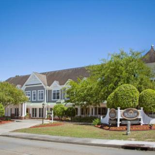 A picturesque hotel building surrounded by well-maintained landscaping under a clear blue sky.