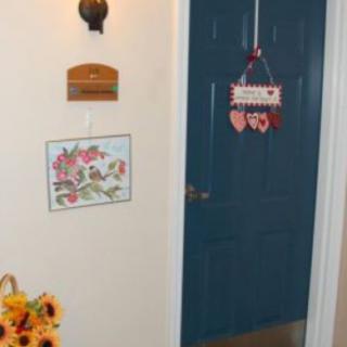 A cozy interior featuring a blue door with wall decorations and a vase of sunflowers.