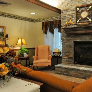 A cozy living room with a stone fireplace, armchair, and decorative elements.