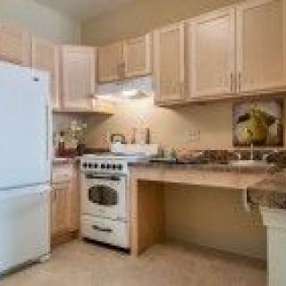 A cozy kitchen featuring wooden cabinets, a white refrigerator, and a stove.