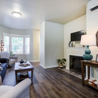 A modern living room with a cozy fireplace, stylish furniture, and wooden flooring.