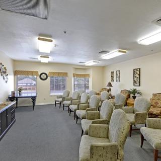 A spacious waiting room with rows of cushioned chairs, well-lit by overhead lighting and natural light from large windows.
